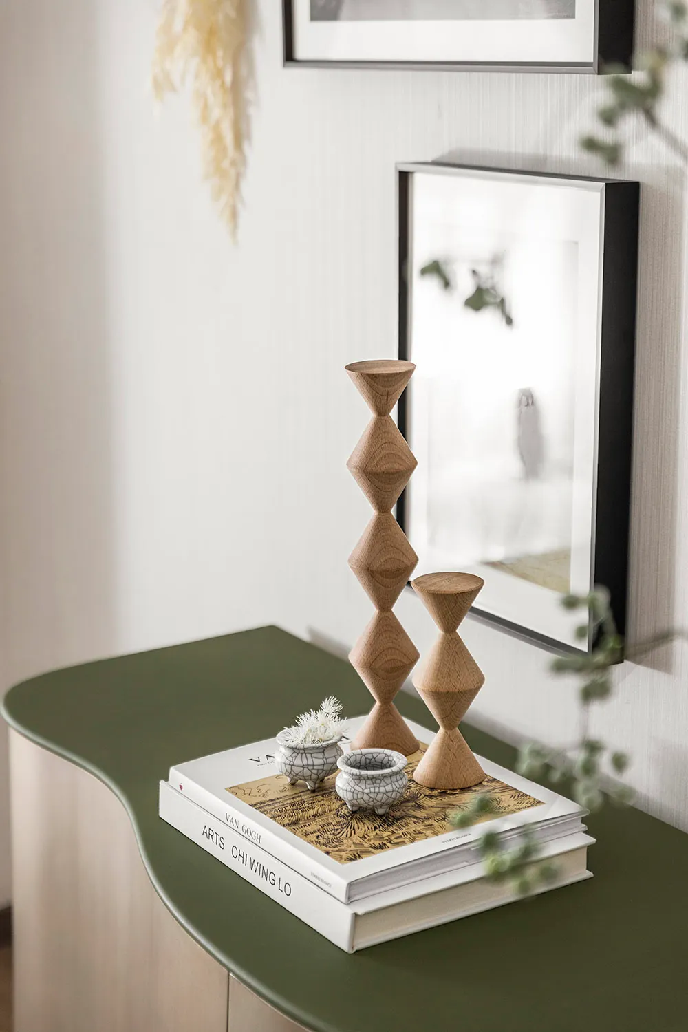 Modern interior design featuring minimalist wooden candlesticks on a green table.