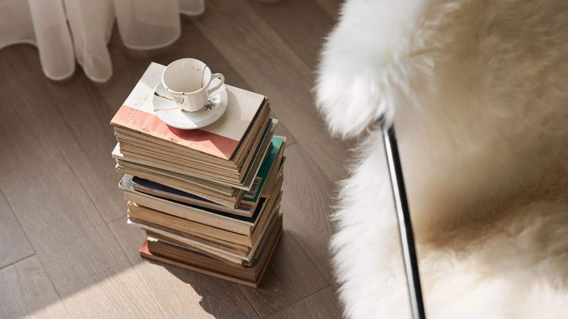 A cozy reading corner with stacked books and a cup of tea on a small table.