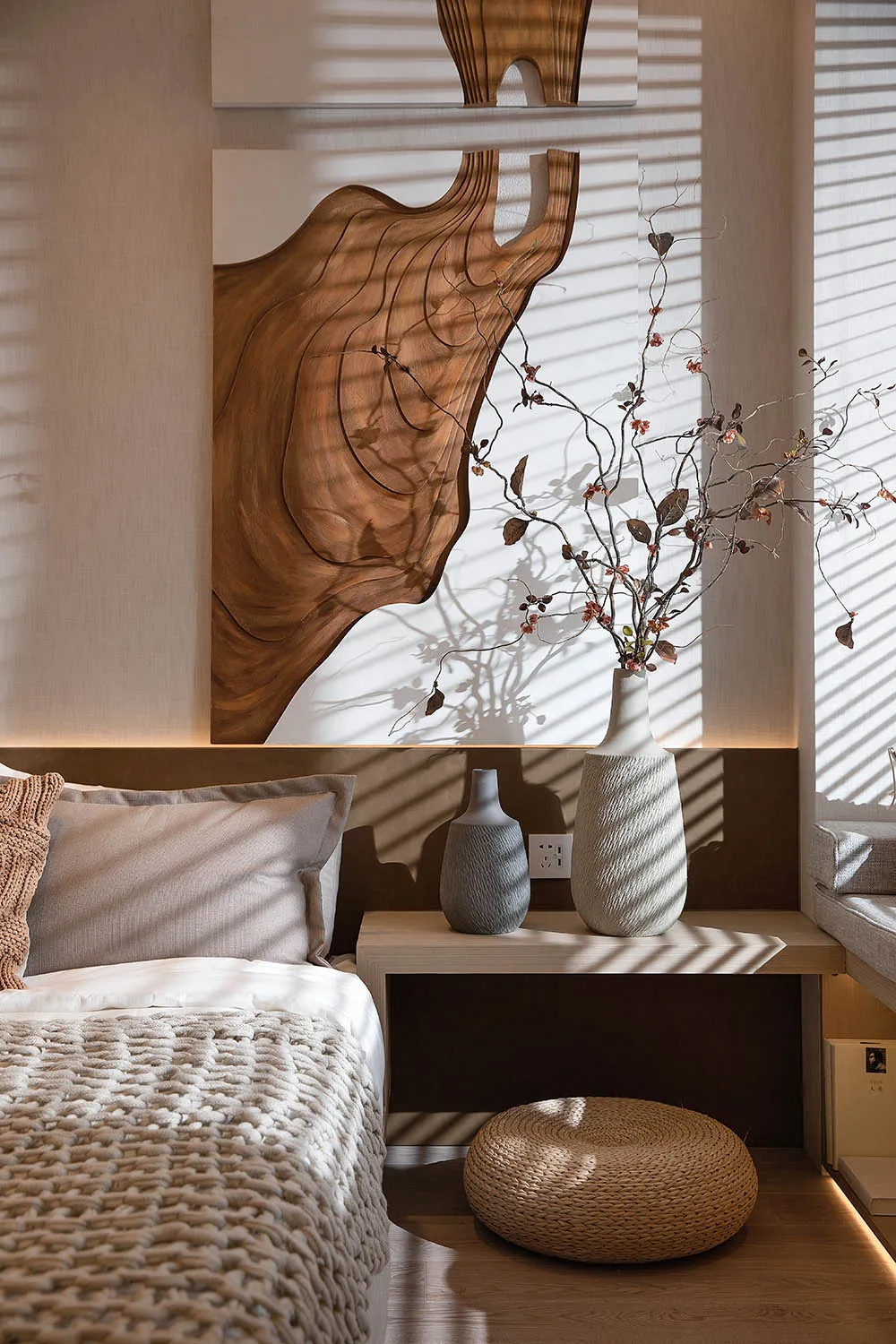 Modern bedroom featuring a bed with a wood-textured headboard, fabric bedding, and ceramic vases on a floating nightstand.