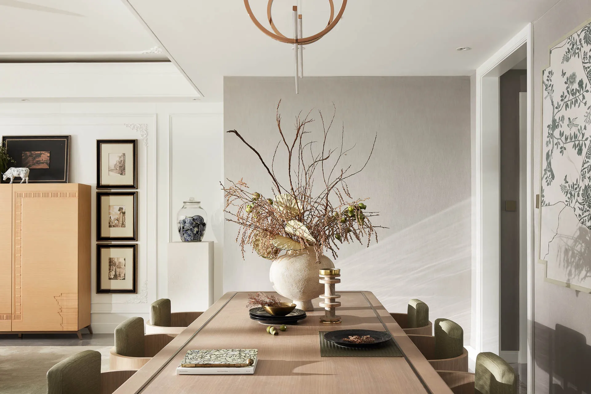 Modern dining room with a long table, chairs, and decorative items on the table.