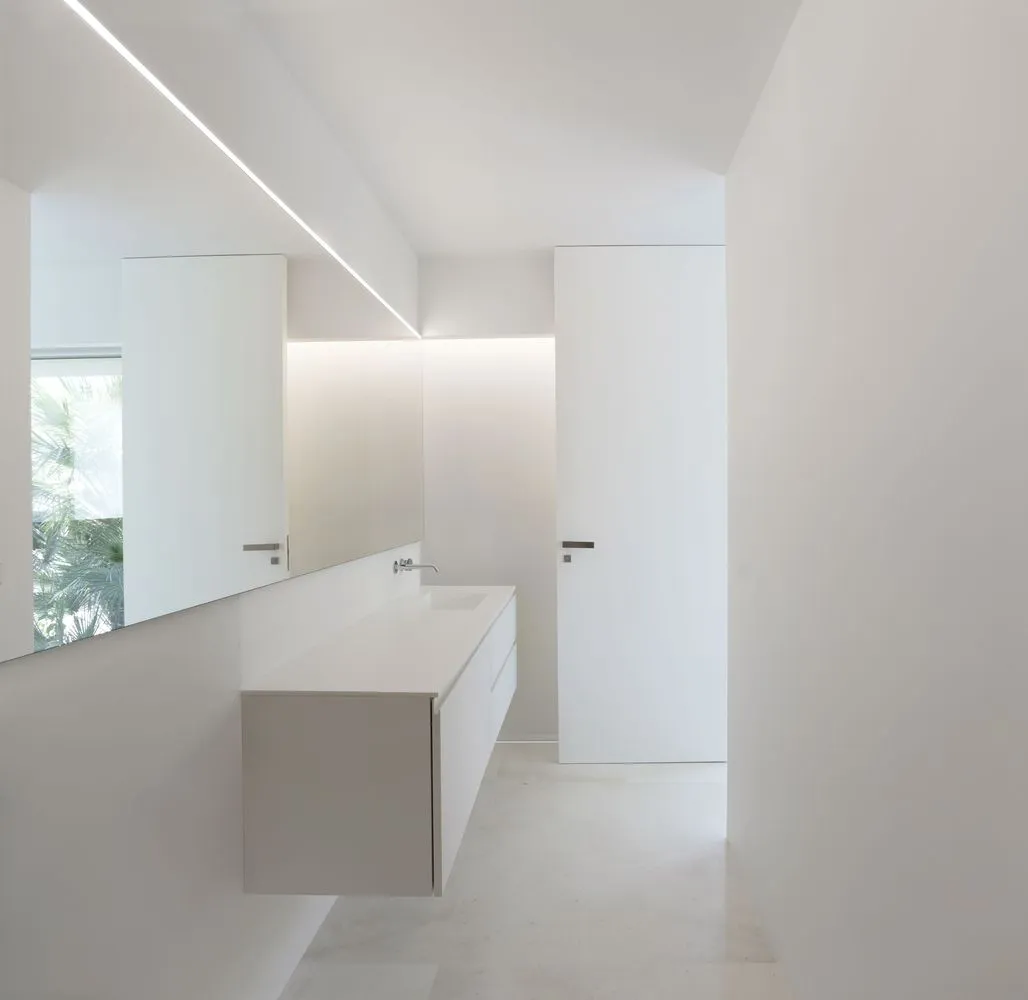 Minimalist bathroom with white walls, featuring a floating vanity and a frosted glass door.