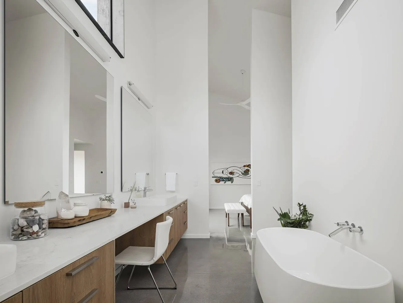 Modern minimalist bathroom with white walls, a white bathtub, and a sleek wooden vanity.