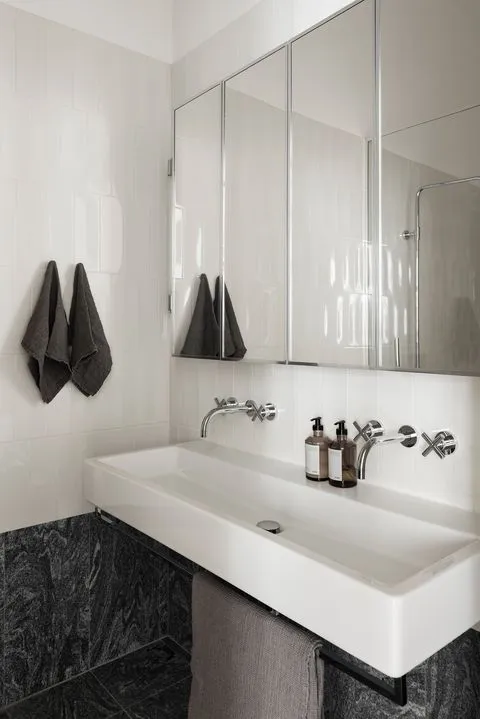 Modern bathroom featuring a white minimalist sink with gray towels and a sleek design.