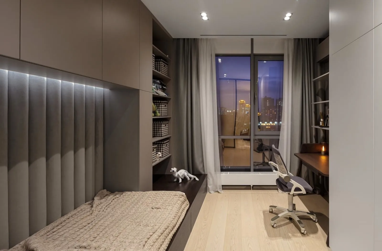 Modern bedroom with wooden flooring, glass window, and fabric furniture