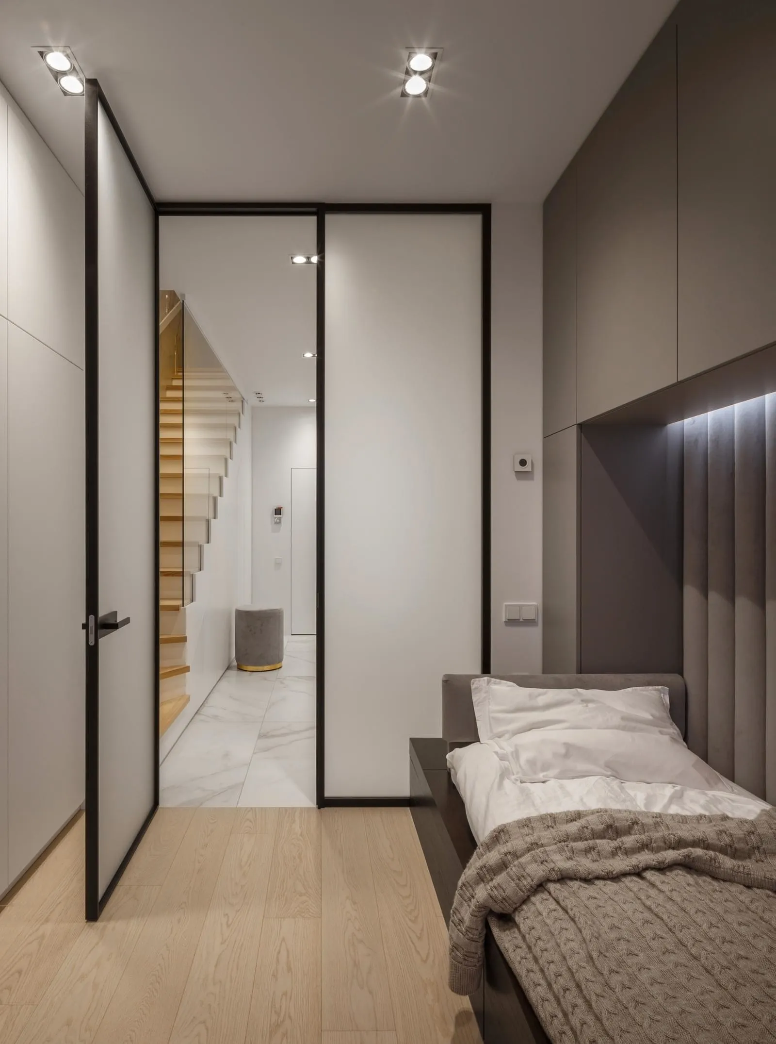 Modern bedroom featuring wooden flooring and marble walls.