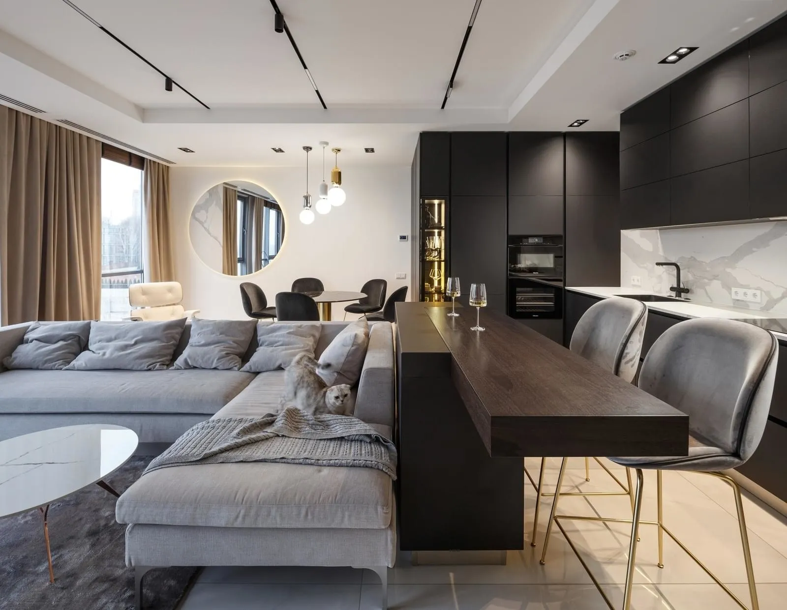 Modern kitchen featuring grey upholstered sofa, grey marble countertops, and black steel kitchen cabinets.