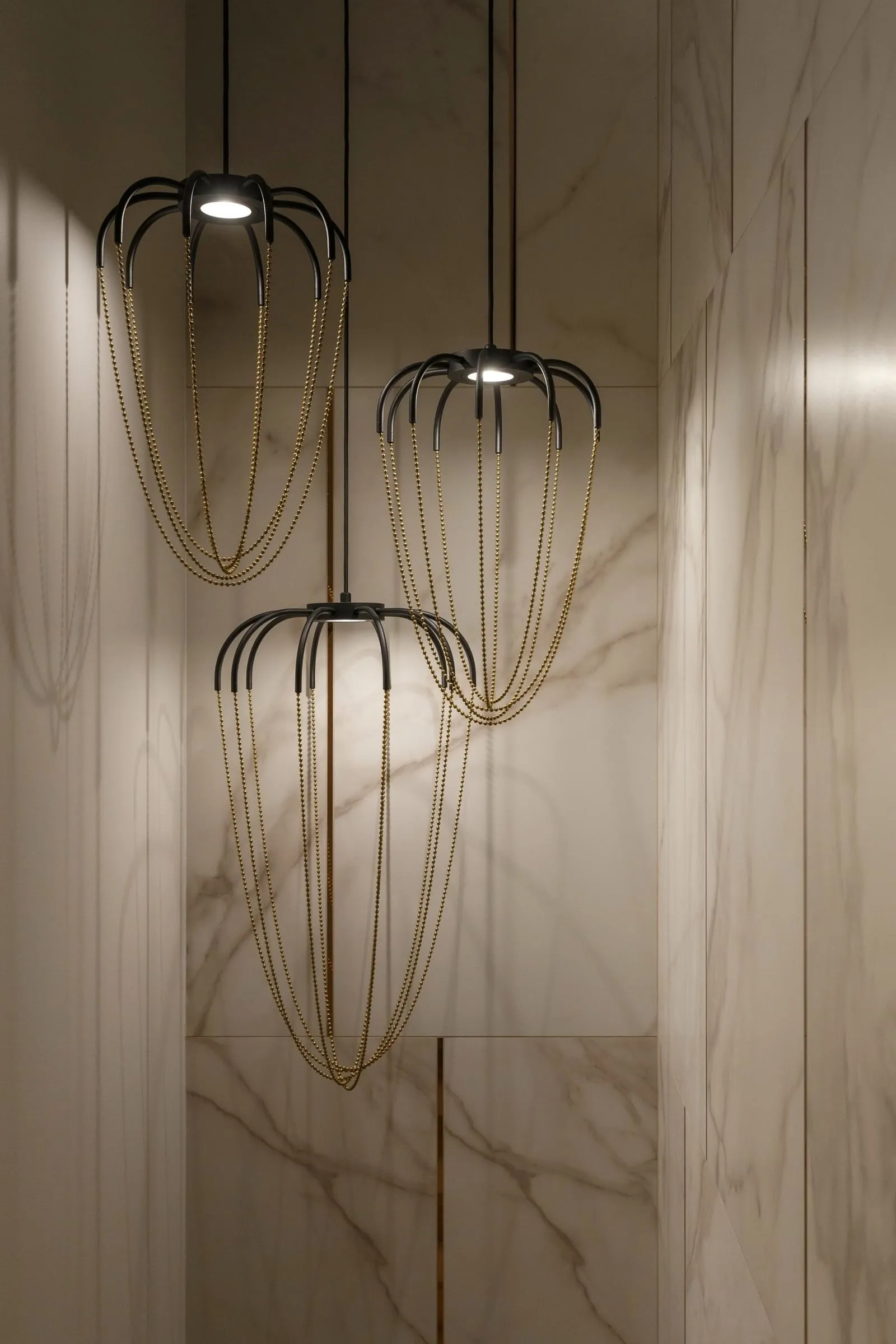 Modern lighting fixtures with metal chains hanging from the ceiling in a modern interior setting.