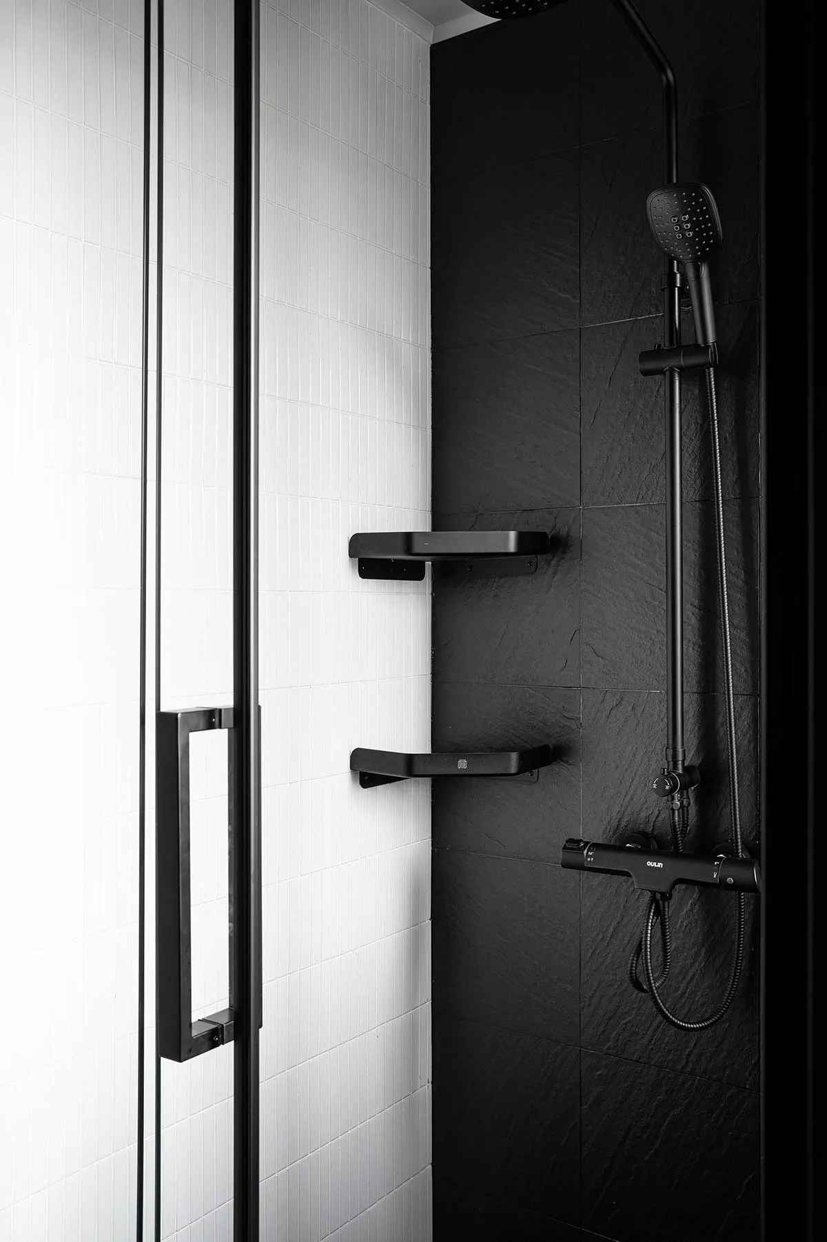 A modern, minimalist bathroom with black and white ceramic tiles, featuring black fixtures and a sleek design.