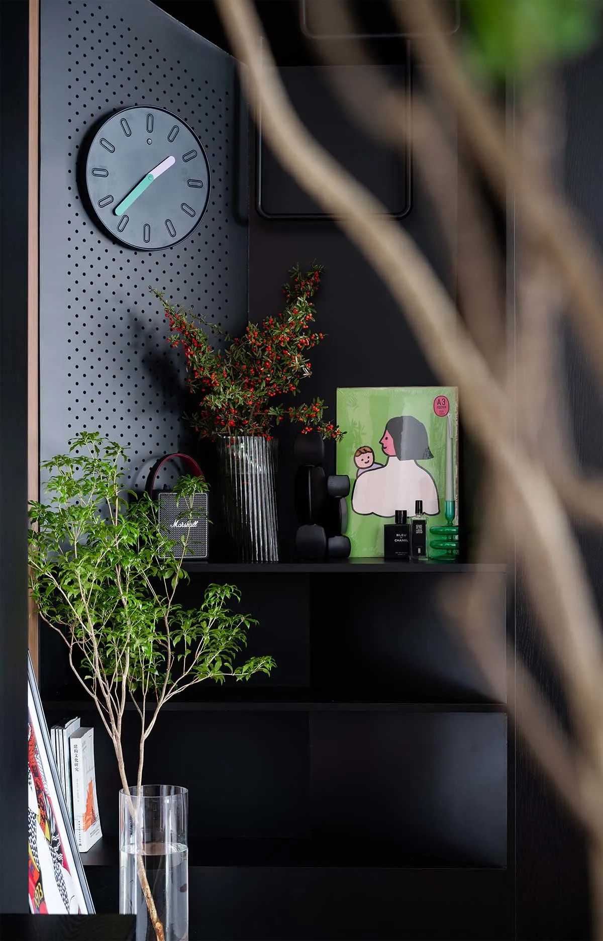 A modern black metal pegboard shelf unit adorned with various decorative items, including a clock, plants, and books.
