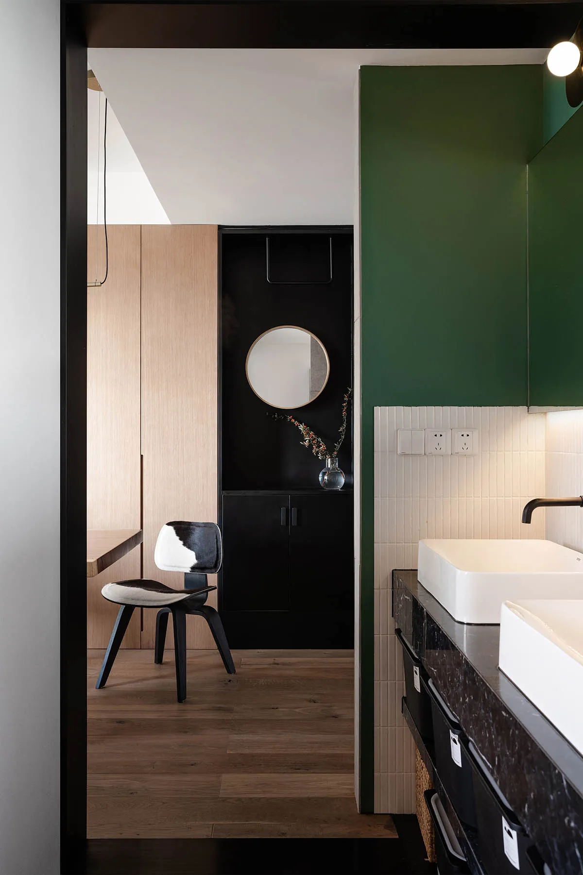 A modern bathroom with green walls, marble countertops, and wooden accents