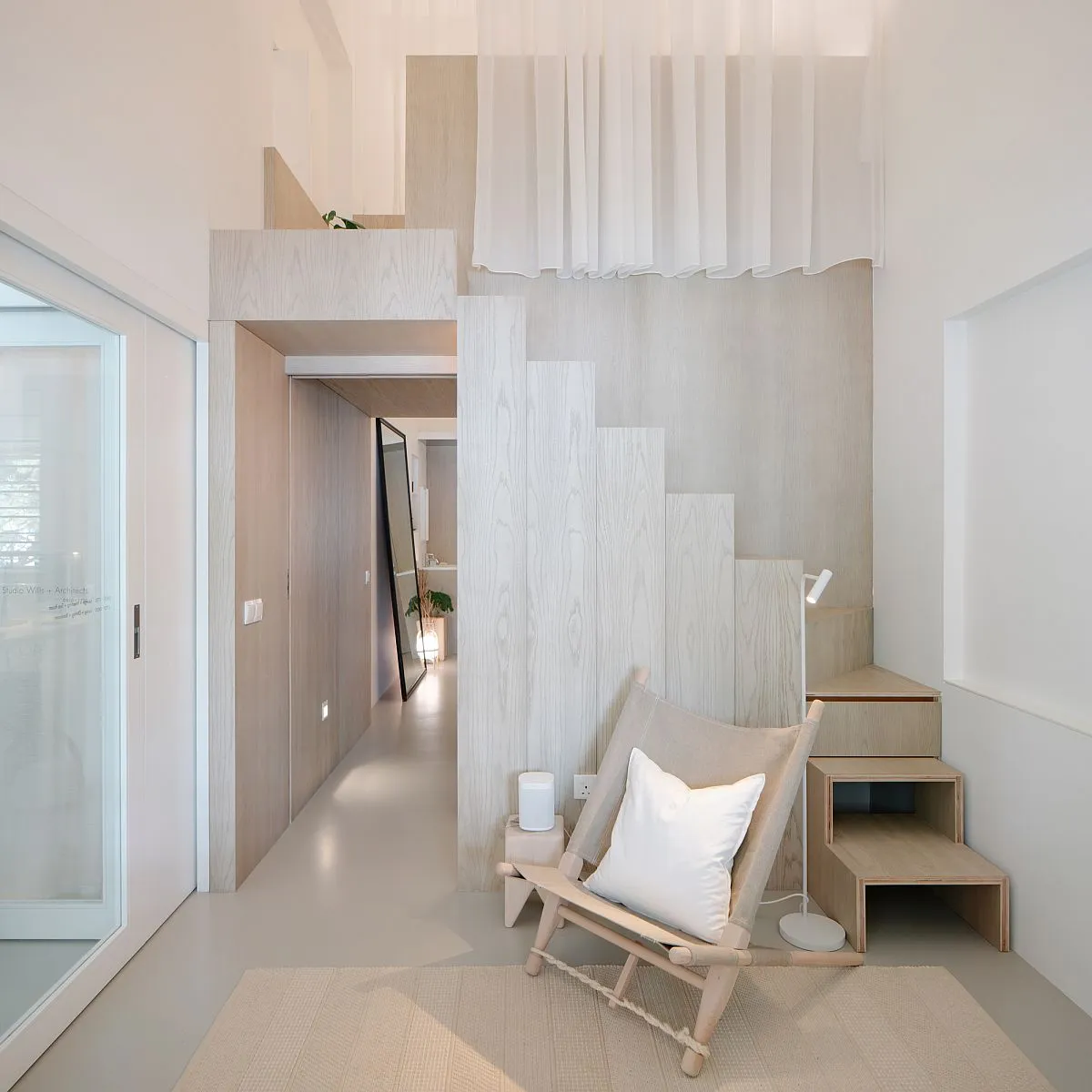 A modern minimalist residential interior featuring wood, glass, and fabric materials.