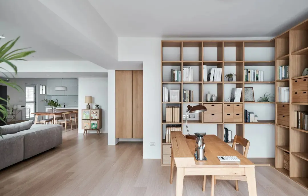 A modern minimalist office space featuring wooden furniture and shelving.