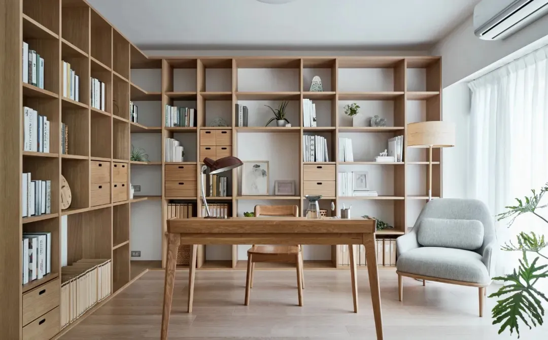 A modern home office featuring a wooden desk, bookshelves, and comfortable furniture.