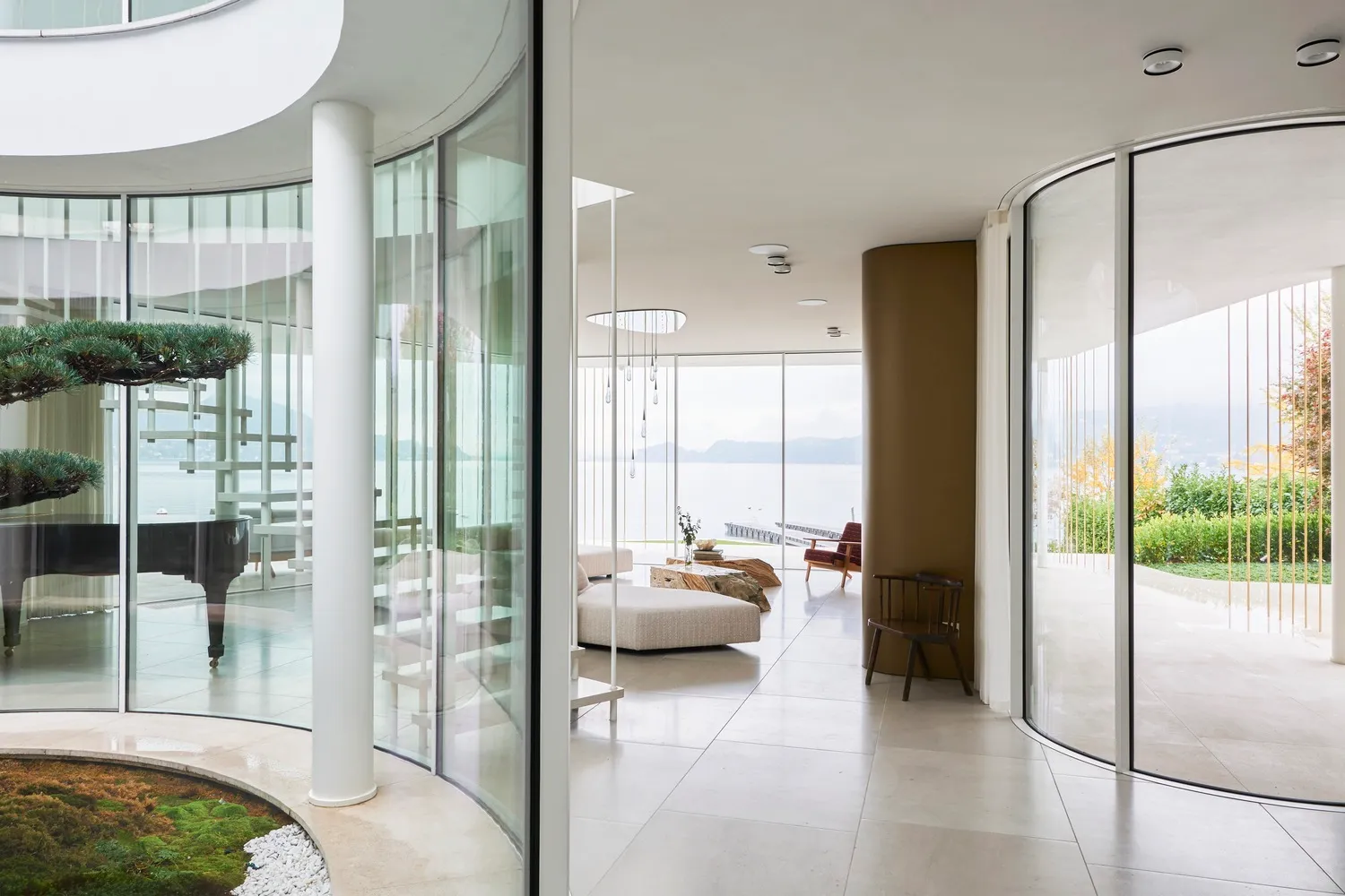 Spacious modern living room with large glass walls overlooking a serene lake