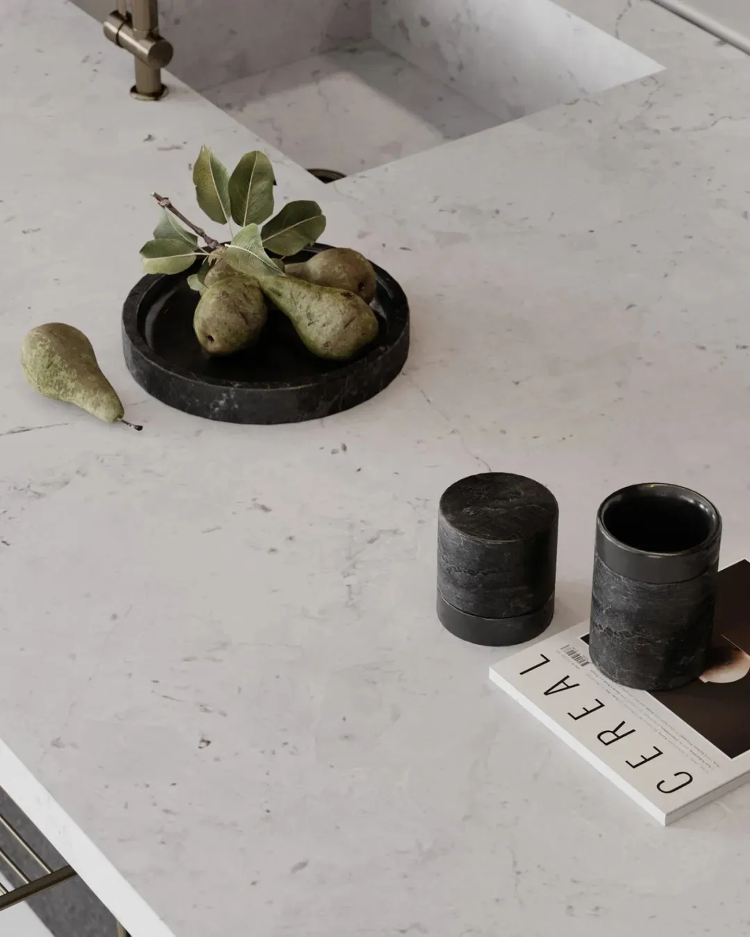 A minimalist interior featuring marble countertops with decorative elements such as green pears and black containers on a whi