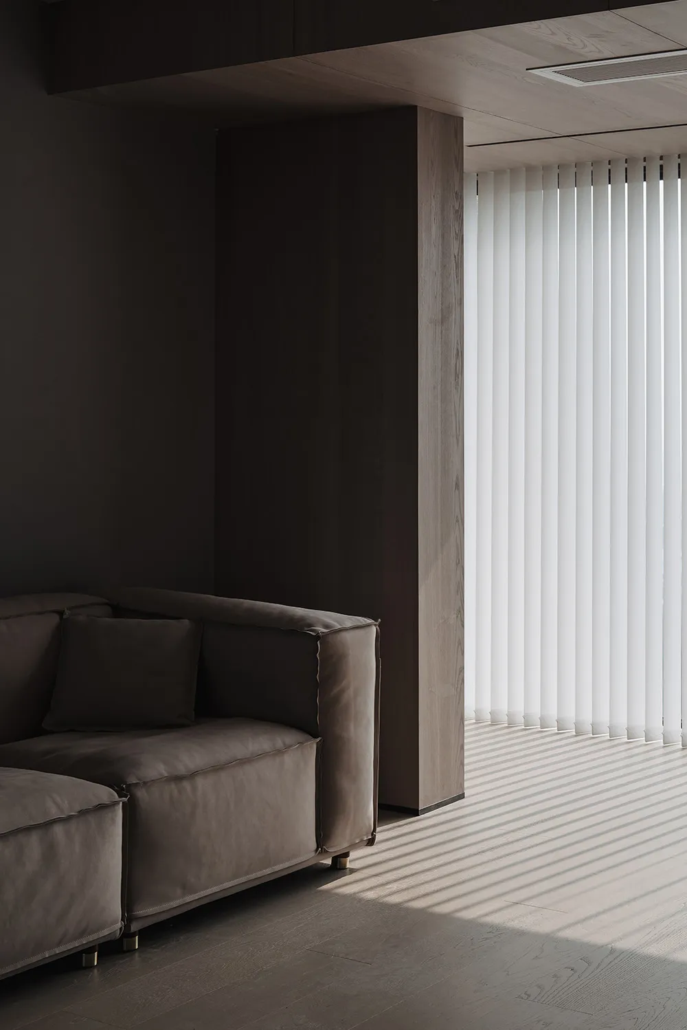 A minimalist residential interior featuring wooden flooring and furniture.