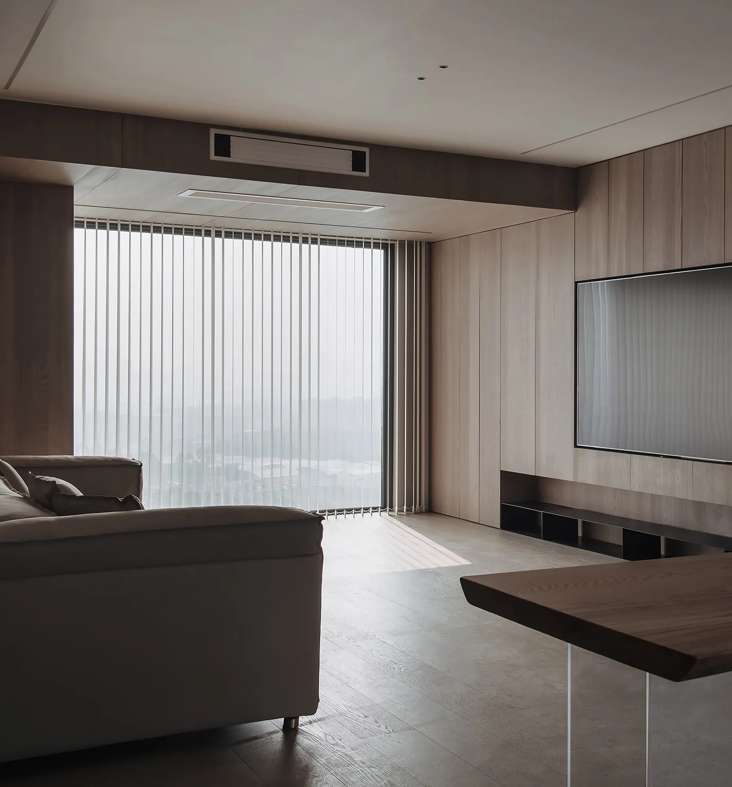 Modern living room featuring minimalist furniture and large windows with vertical blinds.