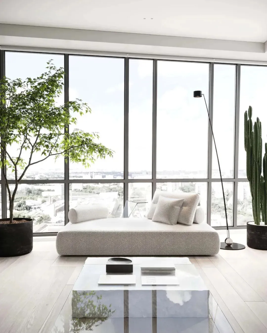 A minimalist living room with a sleek, modern couch, plants, and a coffee table.