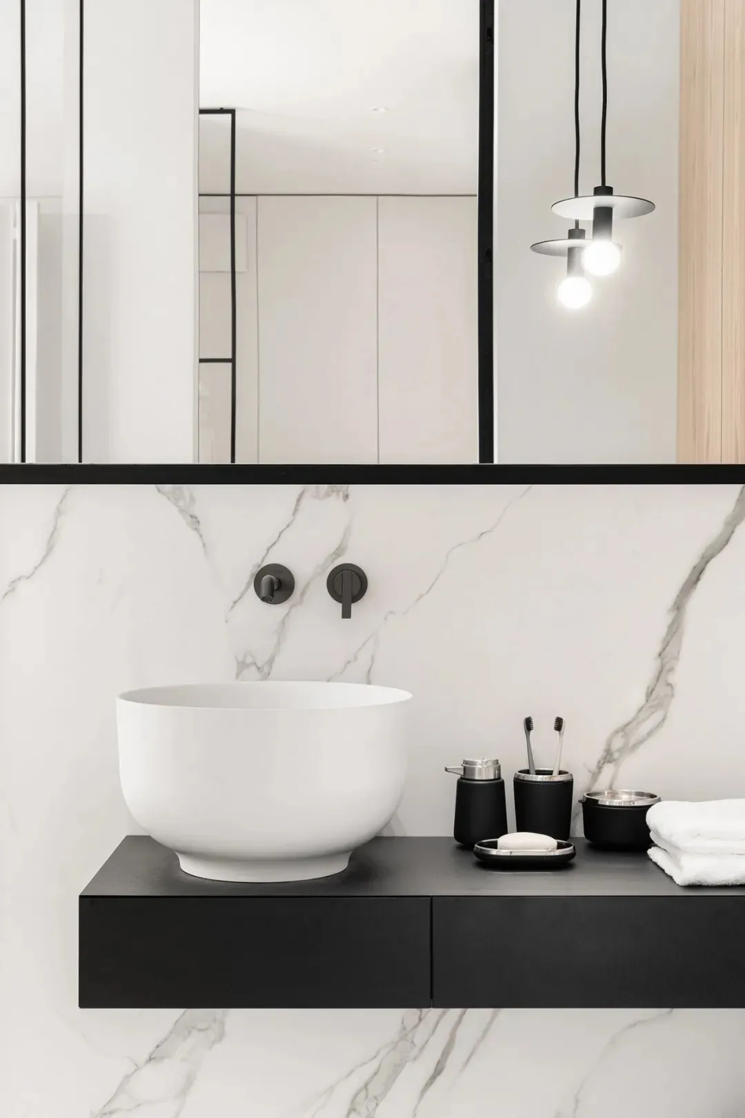 Minimalist bathroom with marble walls, black accents, and contemporary fixtures
