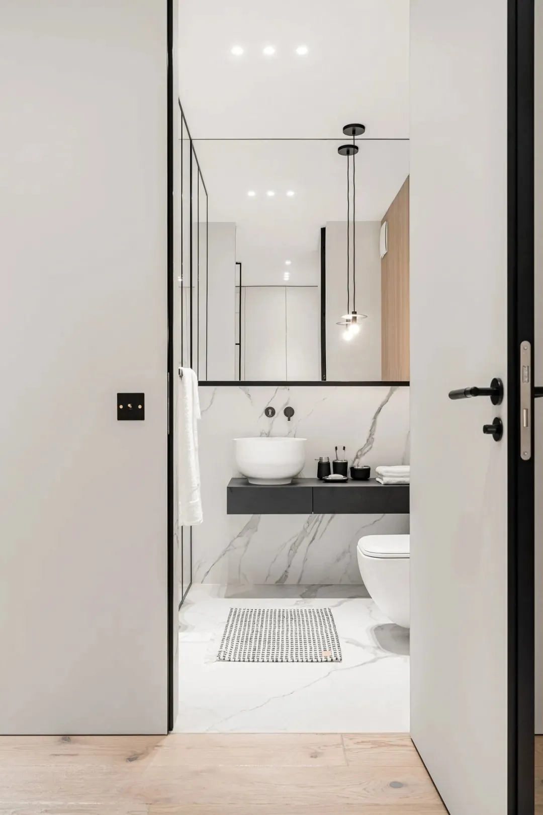 Modern black and marble bathroom with a floating vanity, sink, and toilet.