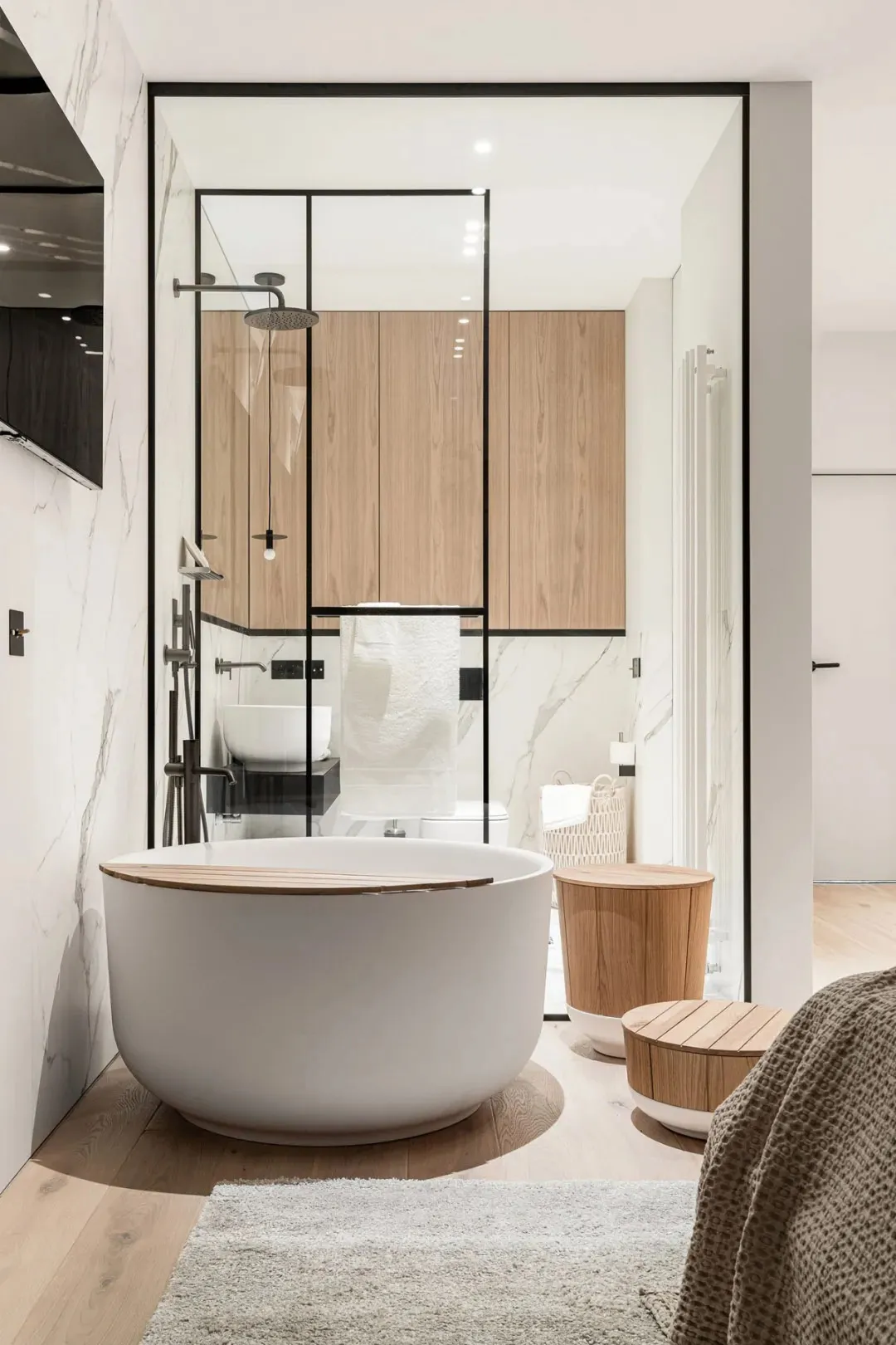 Modern minimalist bathroom with white marble floor, wooden cabinets, and concrete shower surround.