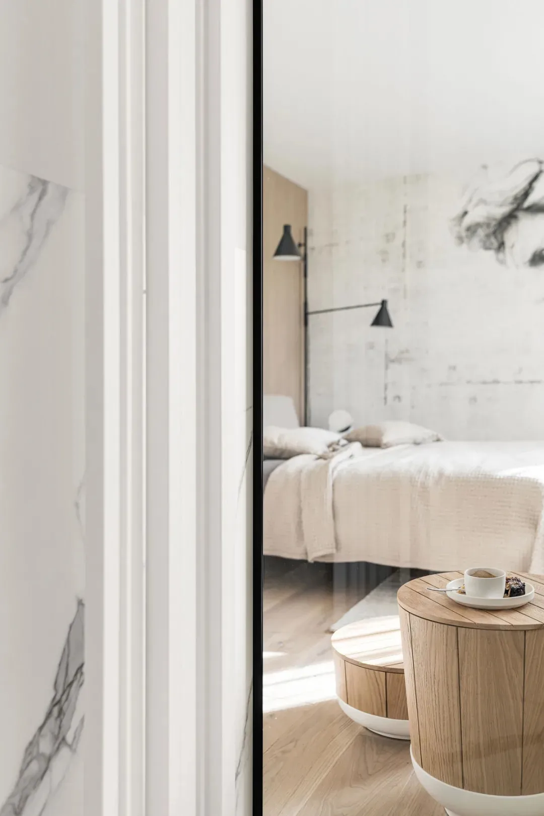 A modern minimalist bedroom featuring marble and wood materials, with a large bed and floating nightstands.