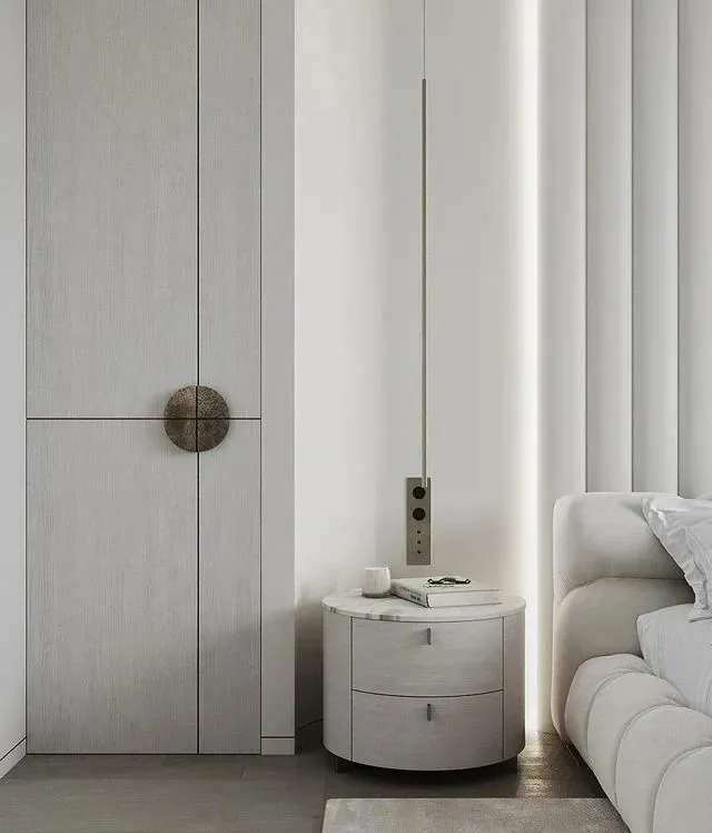 Modern minimalist bedroom featuring white materials, including a sleek round nightstand, a white sofa, and a large window wit