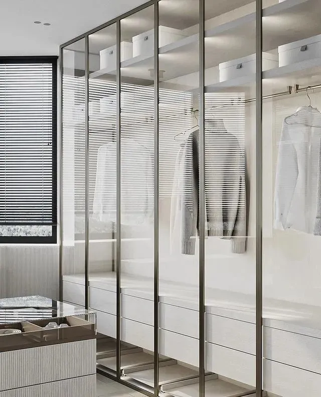Modern minimalist closet with glass doors and white storage units.