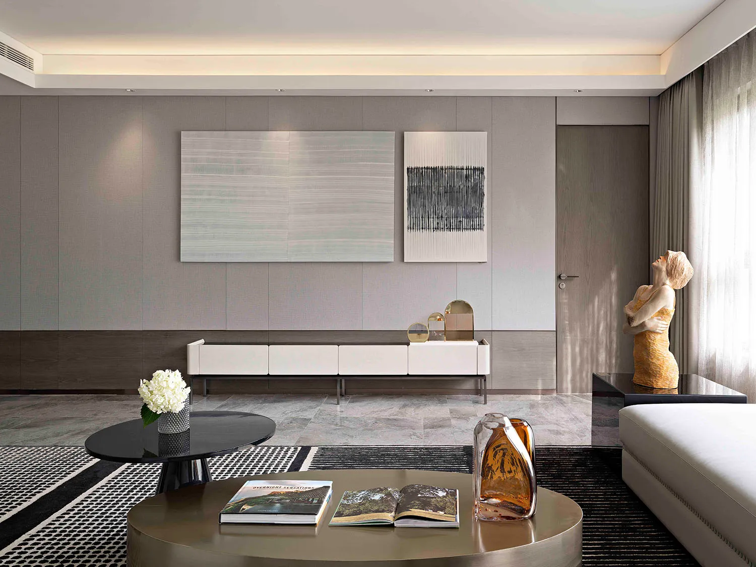 Contemporary living room with modern furniture and minimalist design in neutral tones, featuring abstract wall art and a slee