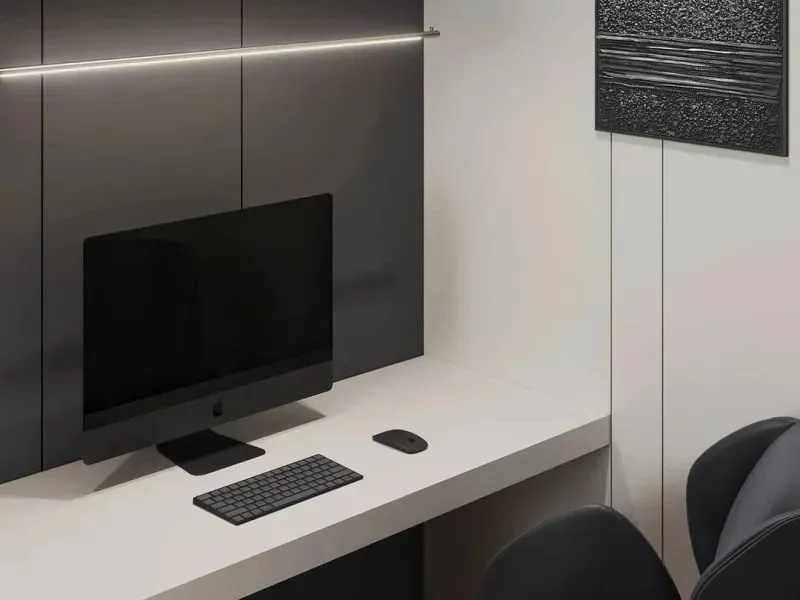A minimalist office space featuring a white desk with a black iMac, a black keyboard, and a black mouse, with concrete walls