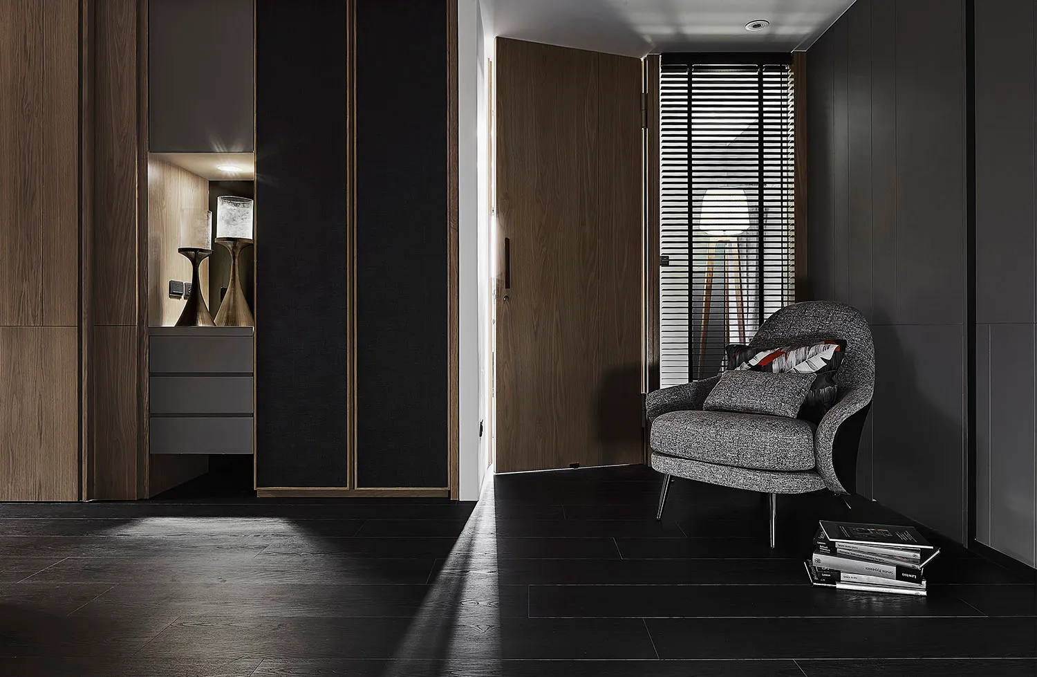 A modern industrial residential entrance with dark wood flooring and a gray upholstered chair.