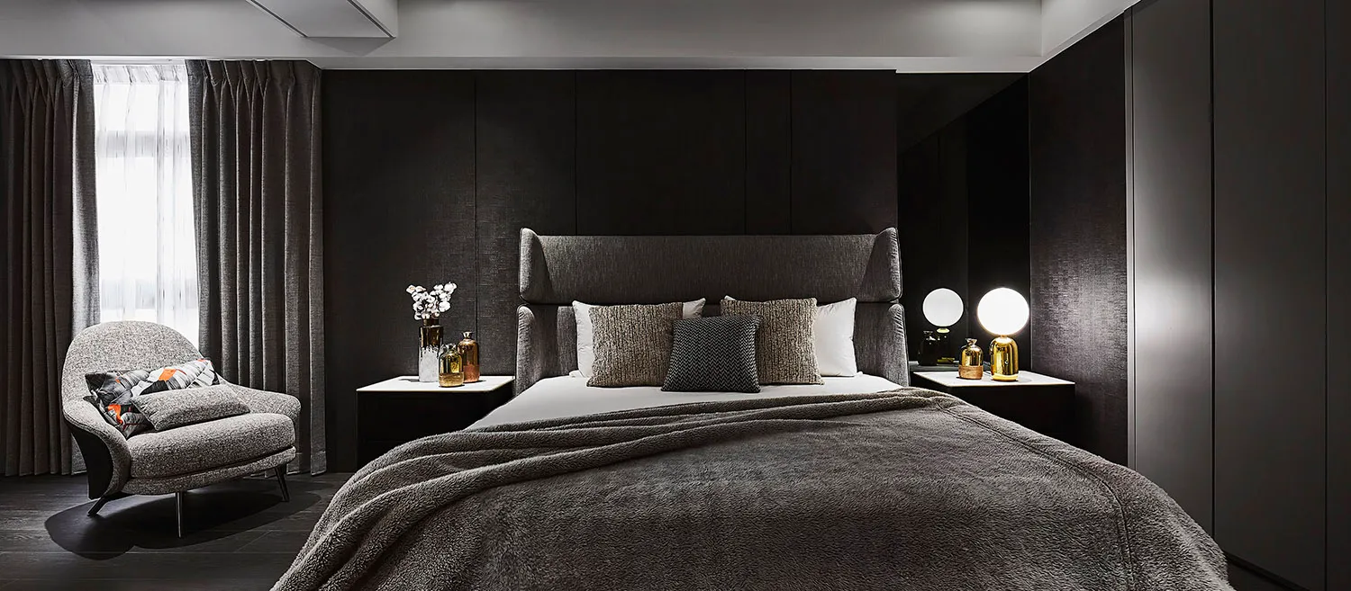 A modern residential bedroom featuring textured fabric upholstery on the bed and armchair.