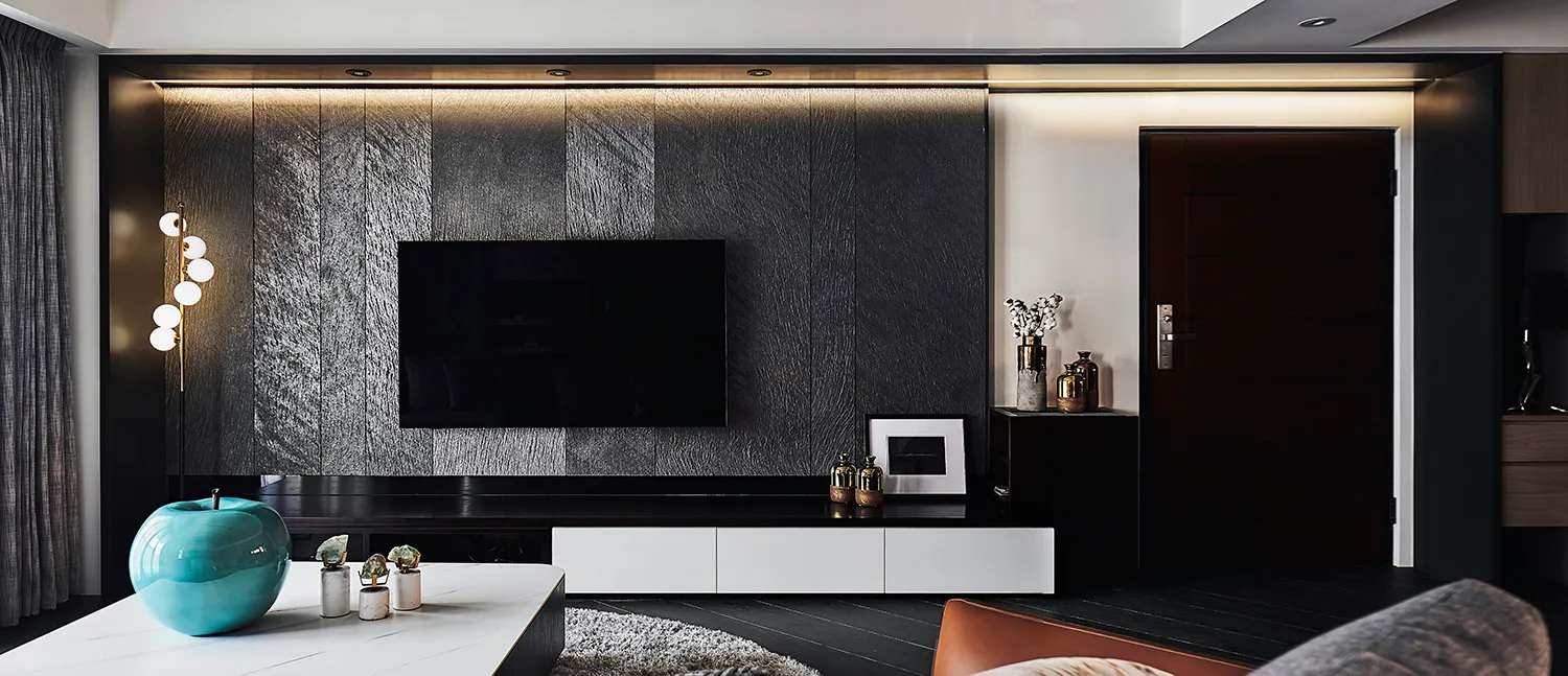 A modern living room featuring metallic texture panels, a flat-screen TV, and minimalist furniture.