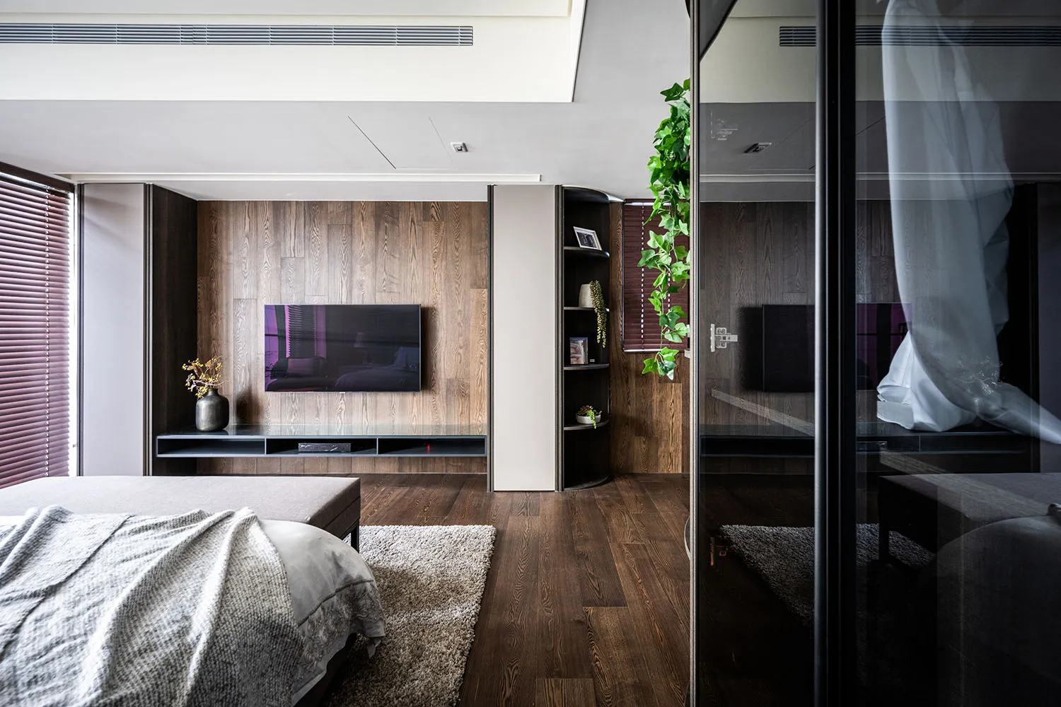 Spacious, minimalist bedroom featuring wood flooring and furniture.