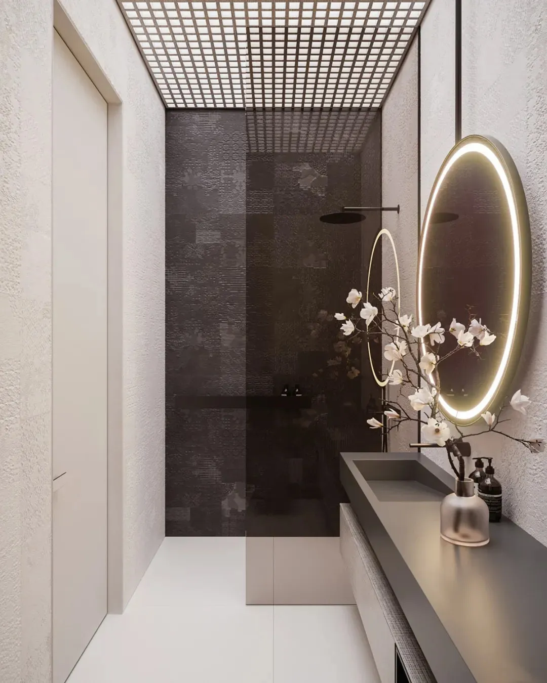 Modern bathroom with dark tiled walls, a sleek sink counter, and a round mirror with illuminated edges.