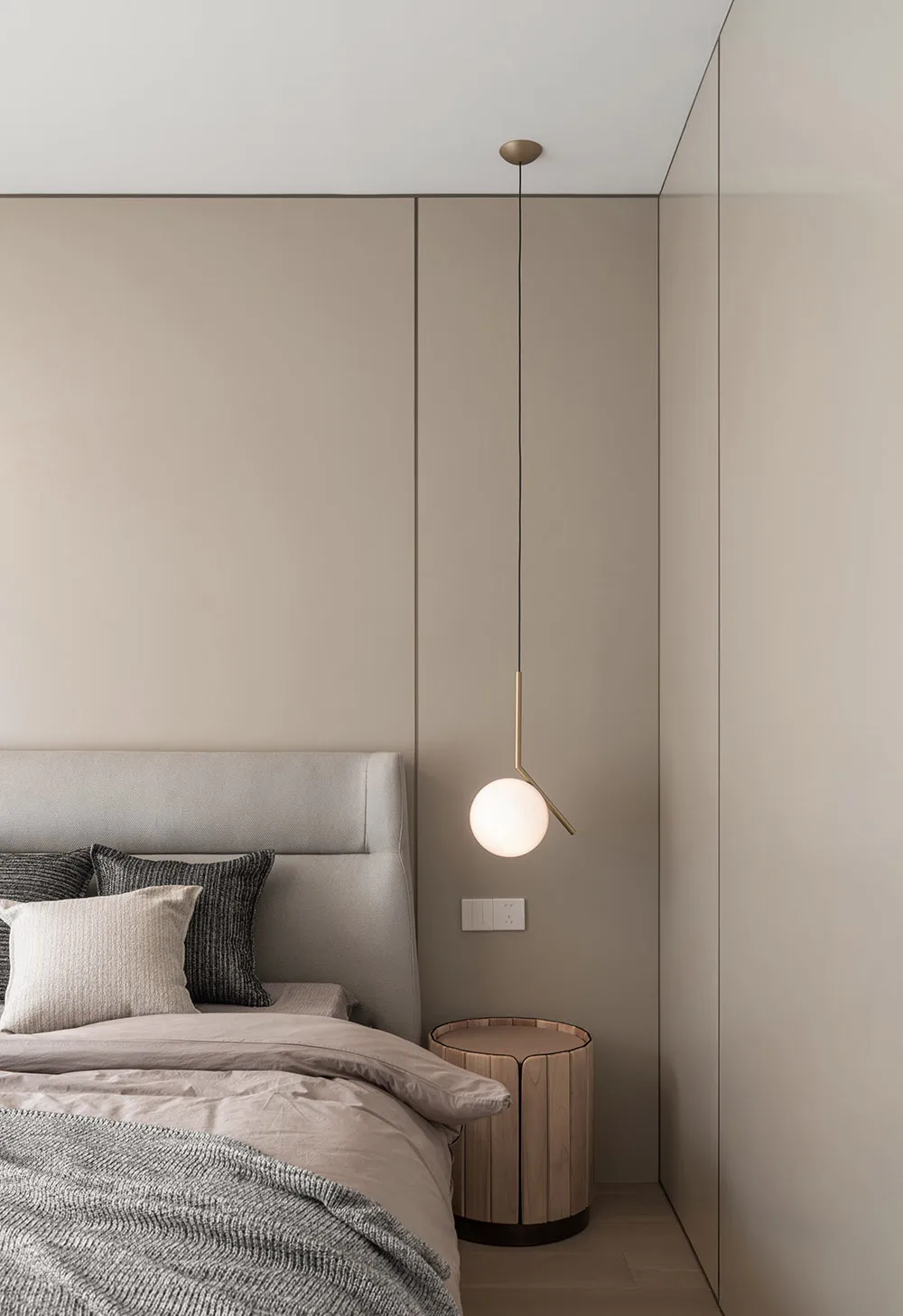 Minimalist bedroom with a wooden bed, side table, and hanging lamp.