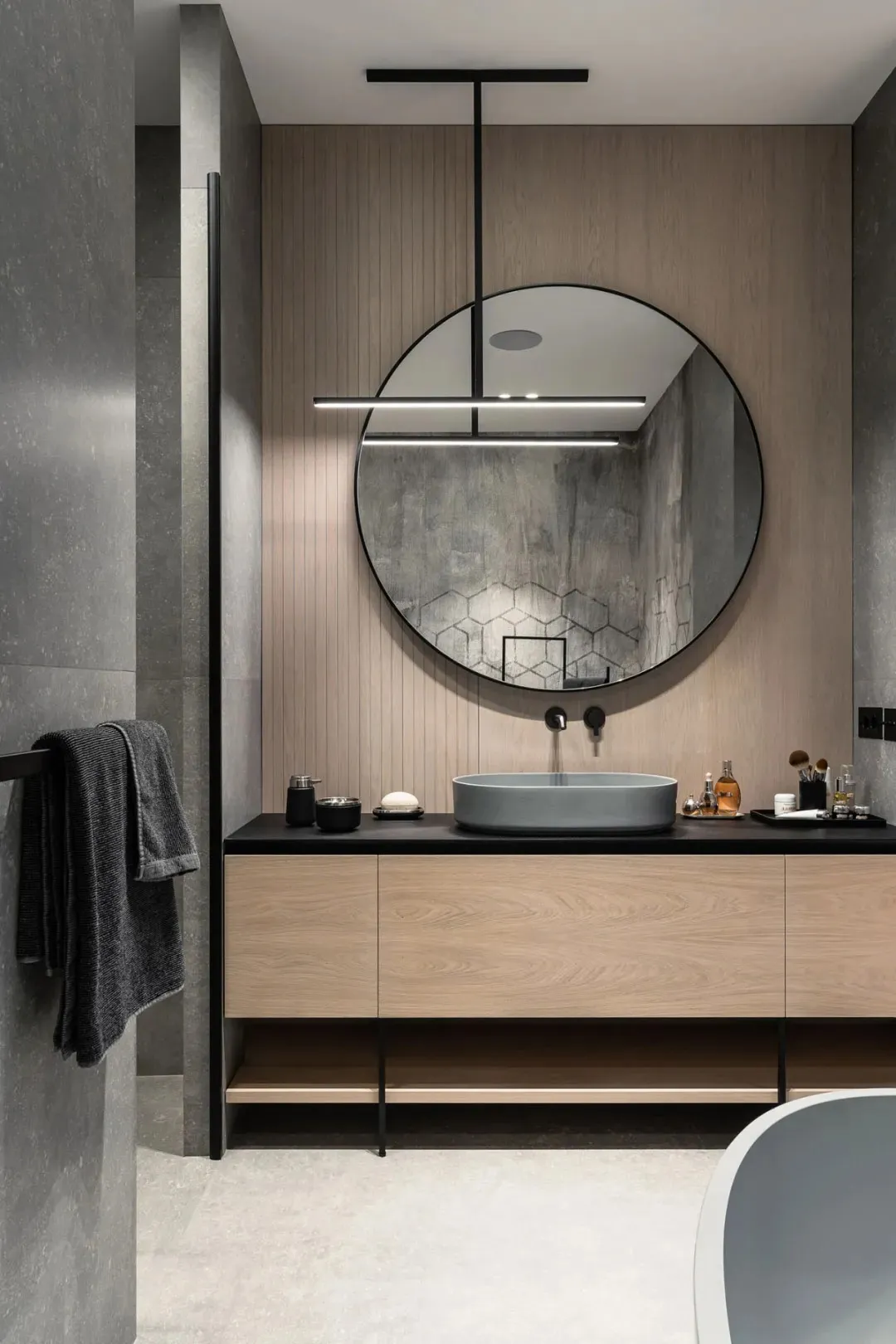 Modern bathroom with concrete mix materials, featuring a circular mirror and a floating vanity sink.