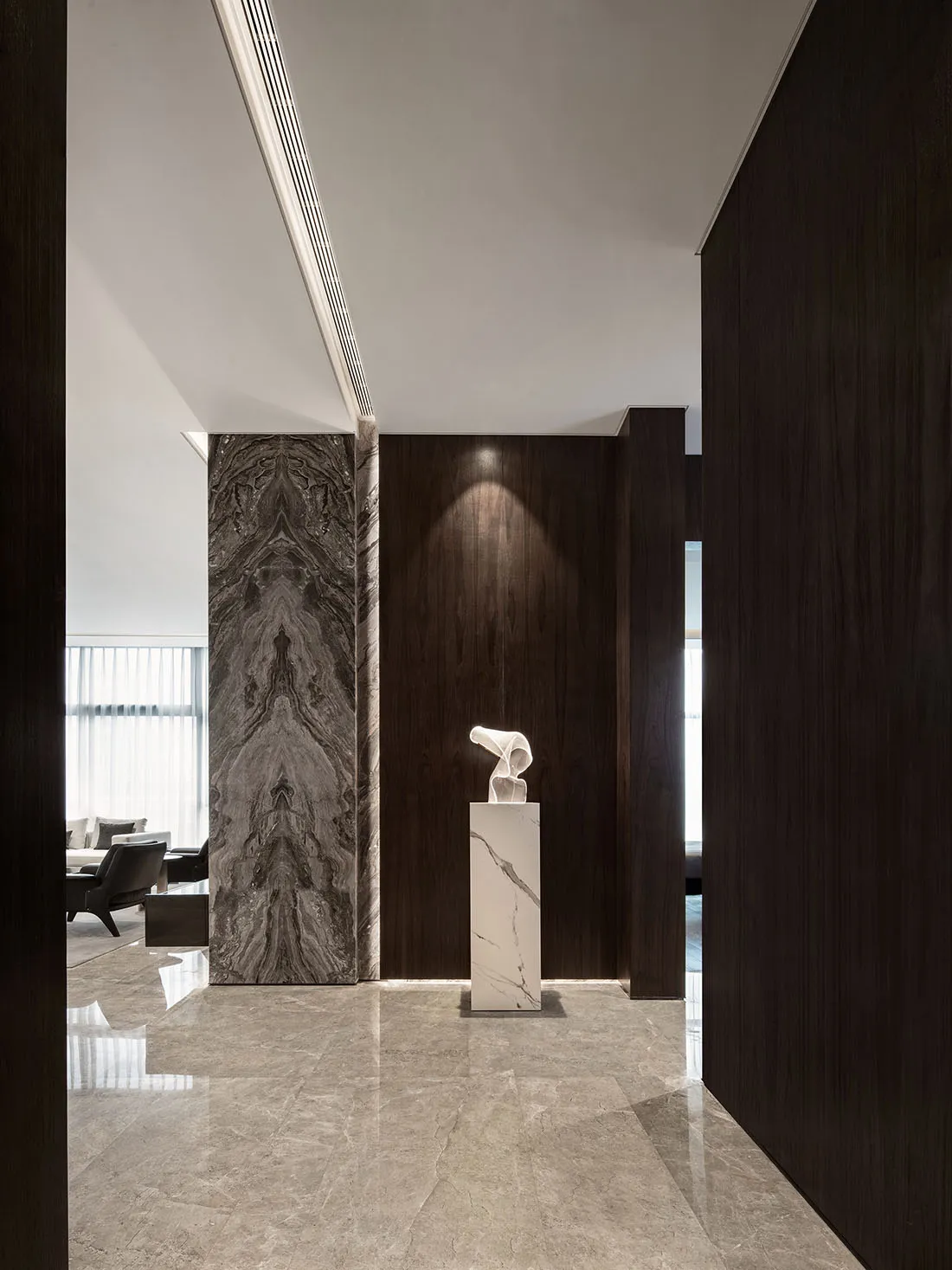 Modern entrance hall with marble flooring, walls, and art display.