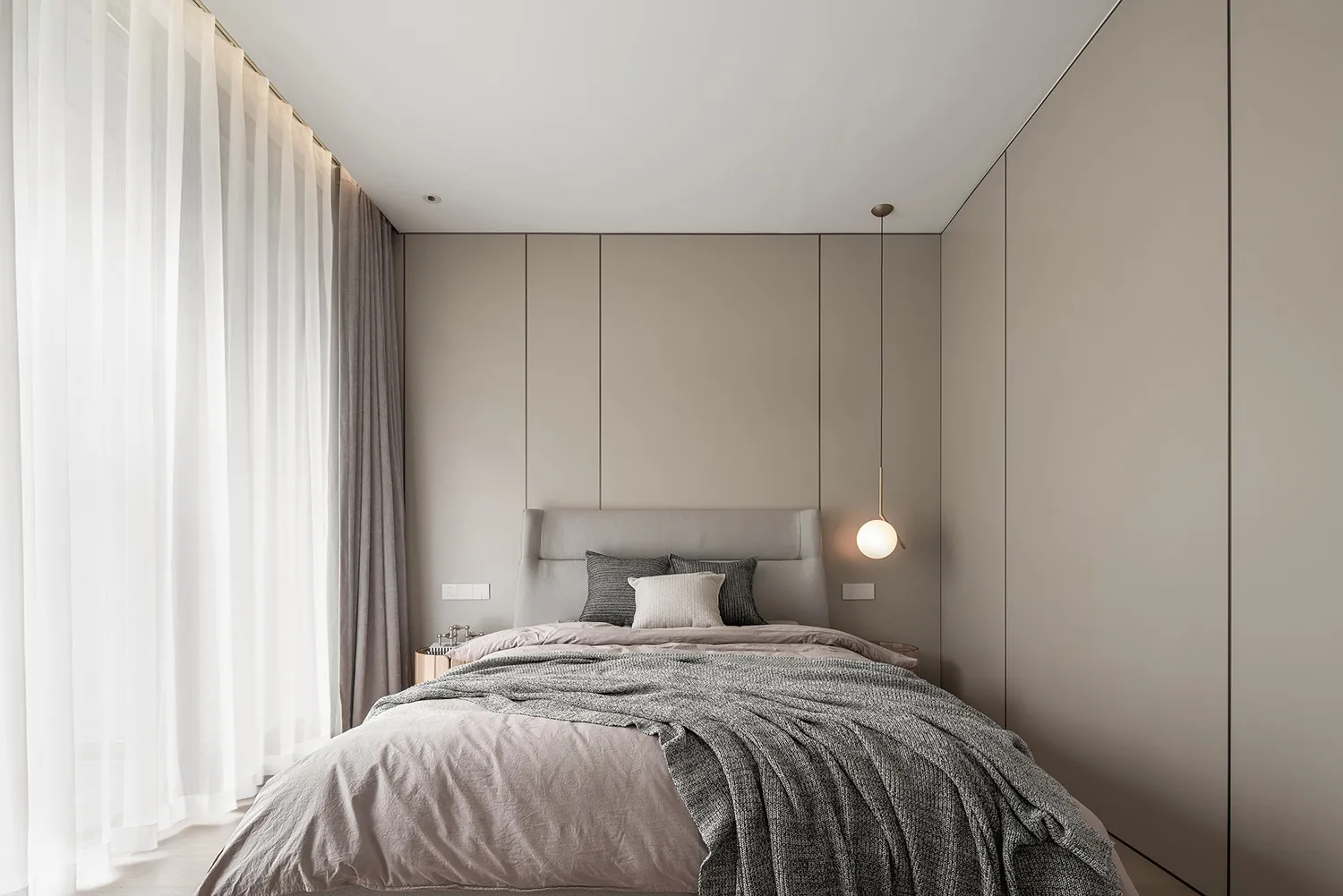 Modern minimalist bedroom featuring taupe textiles and a sleek, clean design.