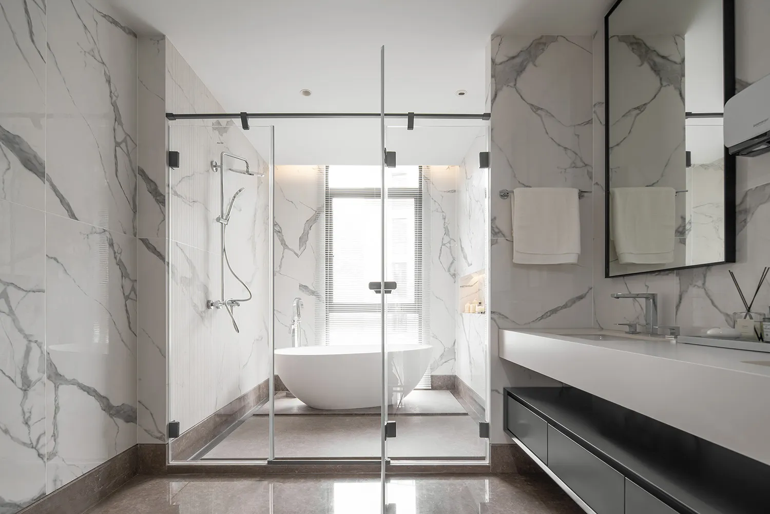 Modern bathroom with marble walls and floor, glass shower enclosure, freestanding bathtub, and floating vanity.