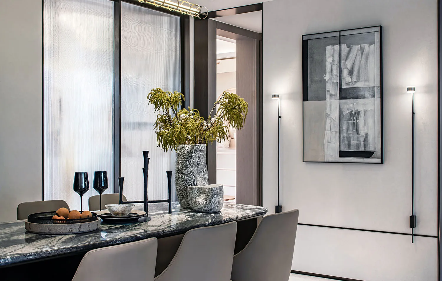 Modern dining room featuring a marble table, chairs, vase with greenery, and abstract art