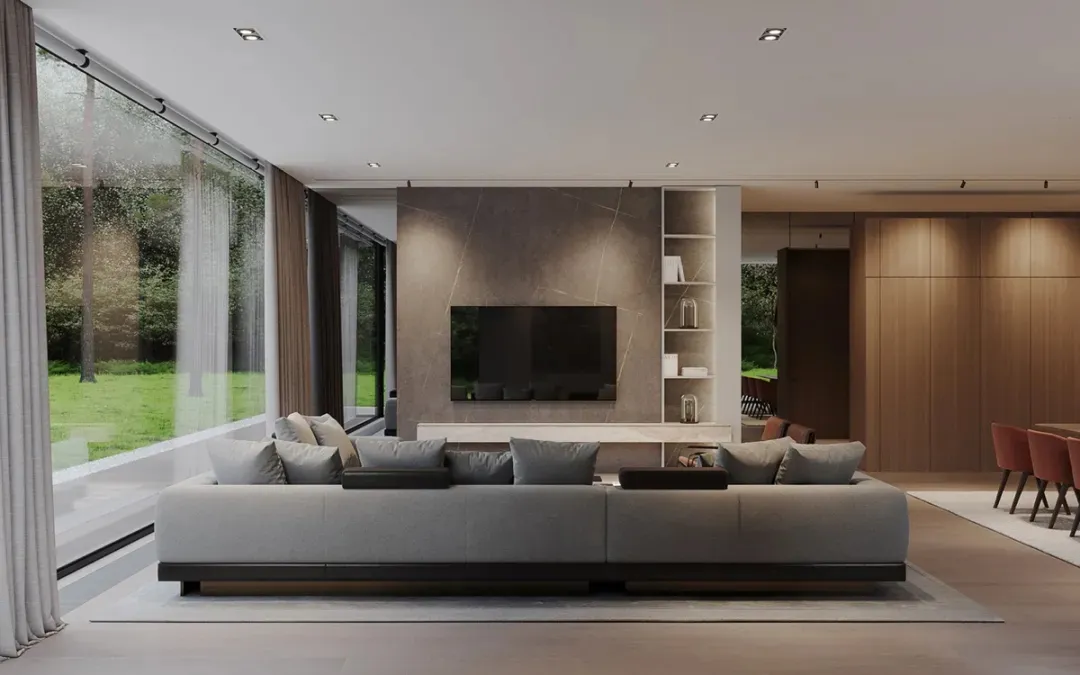 A modern living room featuring a concrete and stone wall with a large sofa and large windows looking out to greenery.