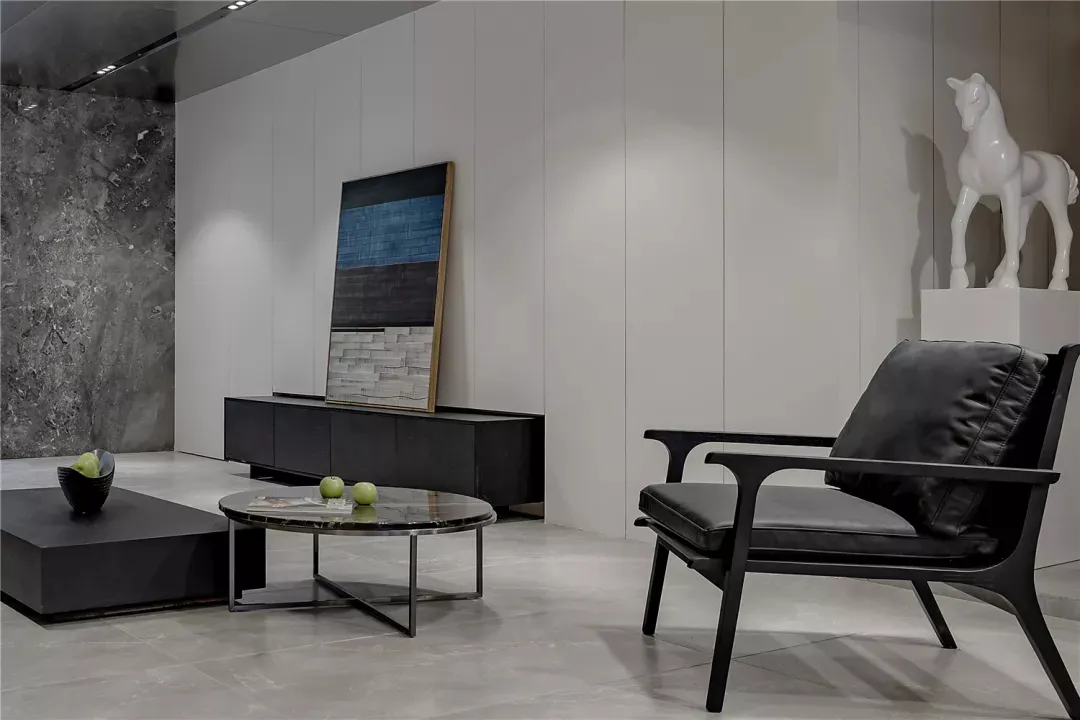 A modern interior with a minimalist design, showcasing black leather furniture on a marble floor.