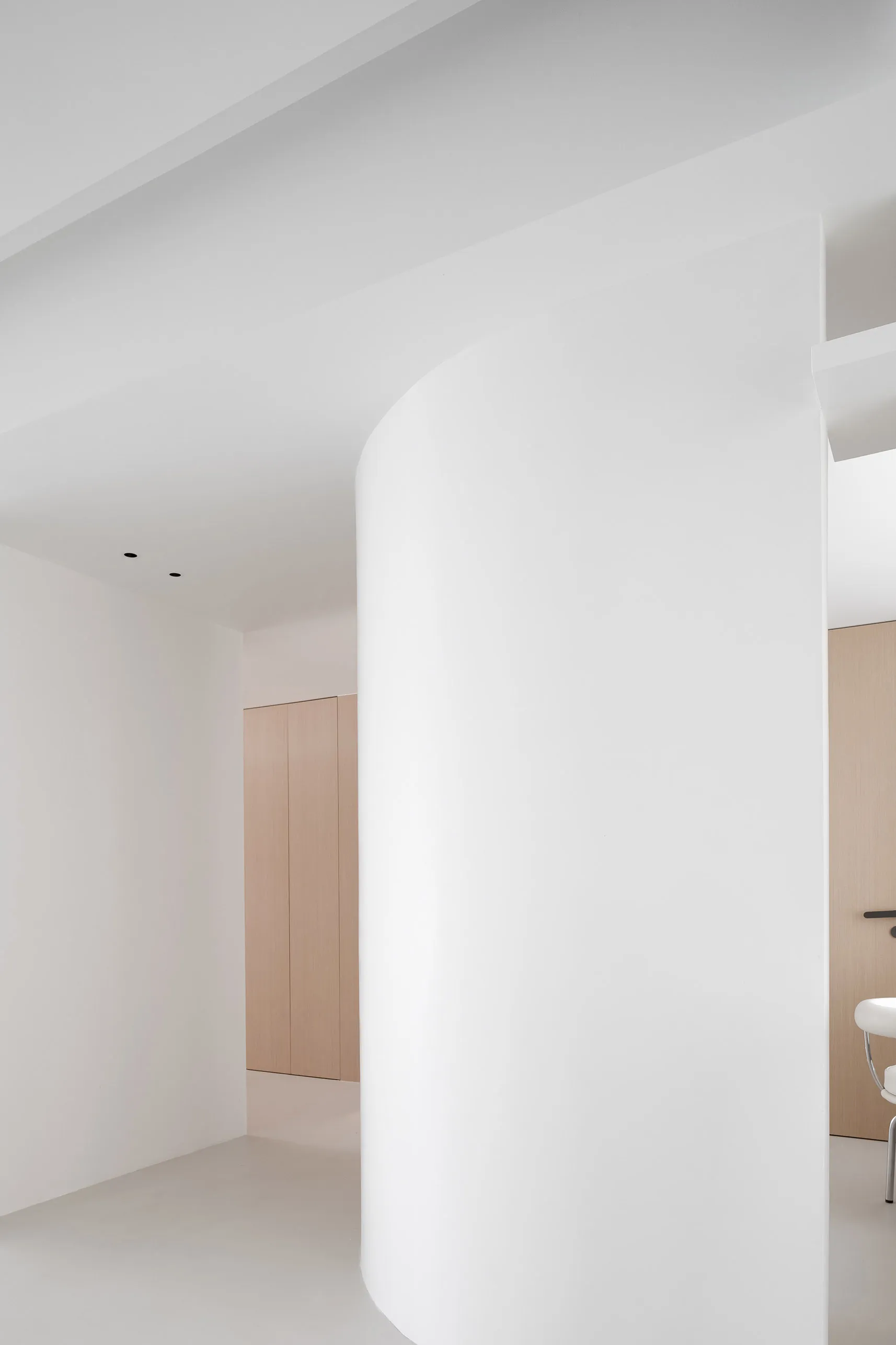 A view of a minimalist modern office interior with white walls, columns, and wood doors.