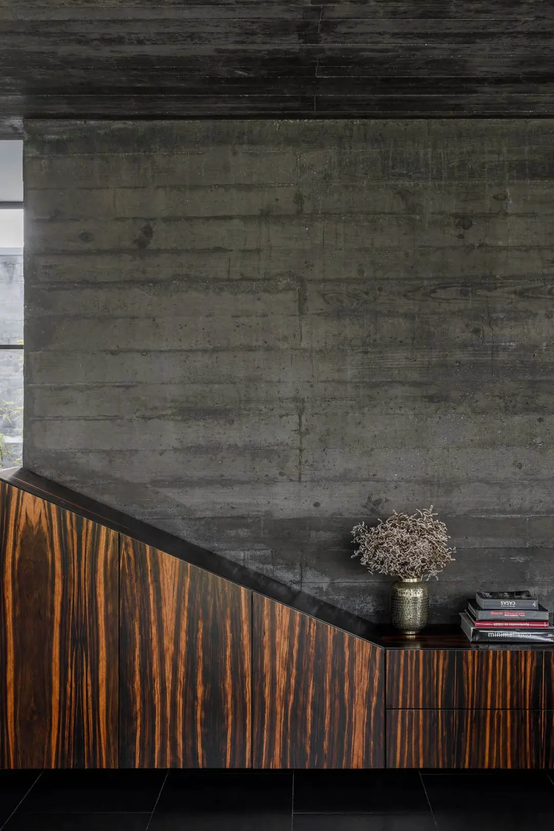 A modern living room with a concrete wall and wooden furniture.