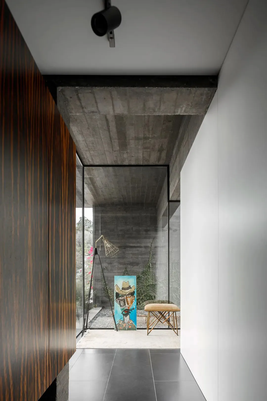 Modern entryway featuring a concrete ceiling, wooden flooring, and a glass and metal bench.