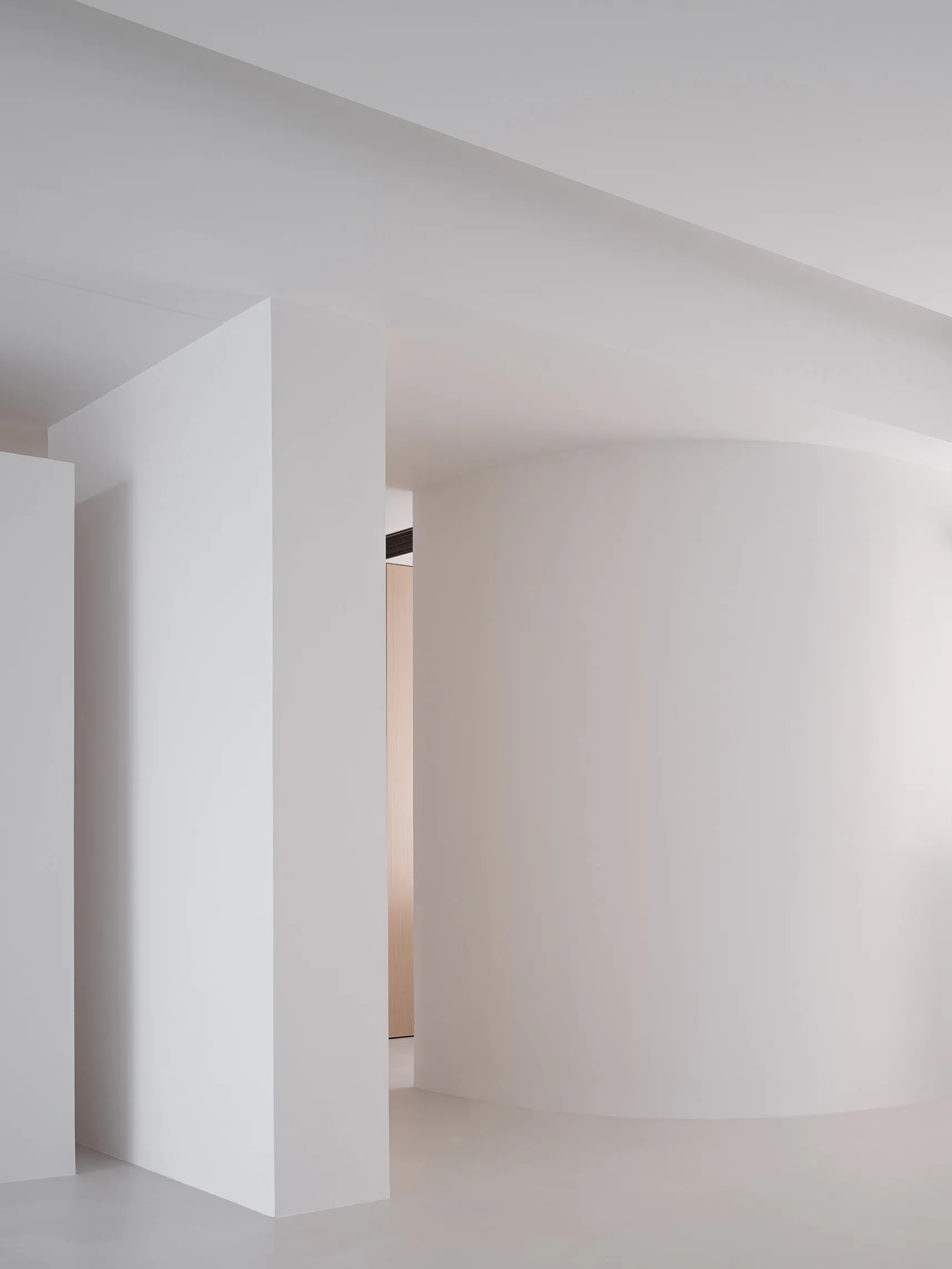 A minimalist white interior with curved walls and a clean, modern design.
