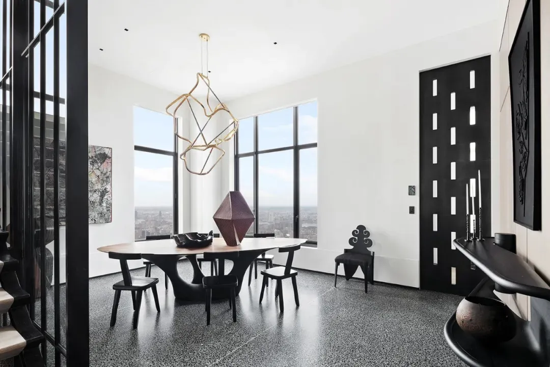 Modern dining room with a metal table and chairs, featuring large windows and a unique pendant light.