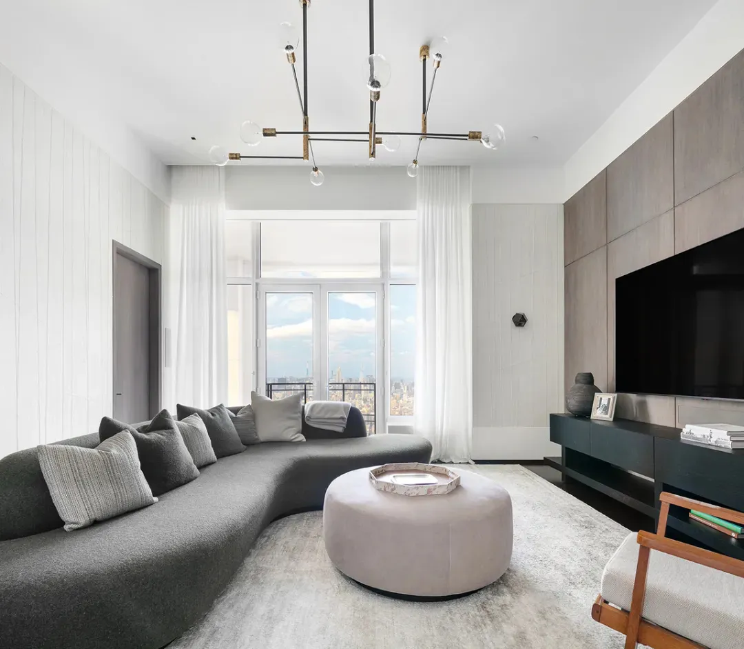 Modern living room featuring glass and wooden furniture and a large window with city skyline view.