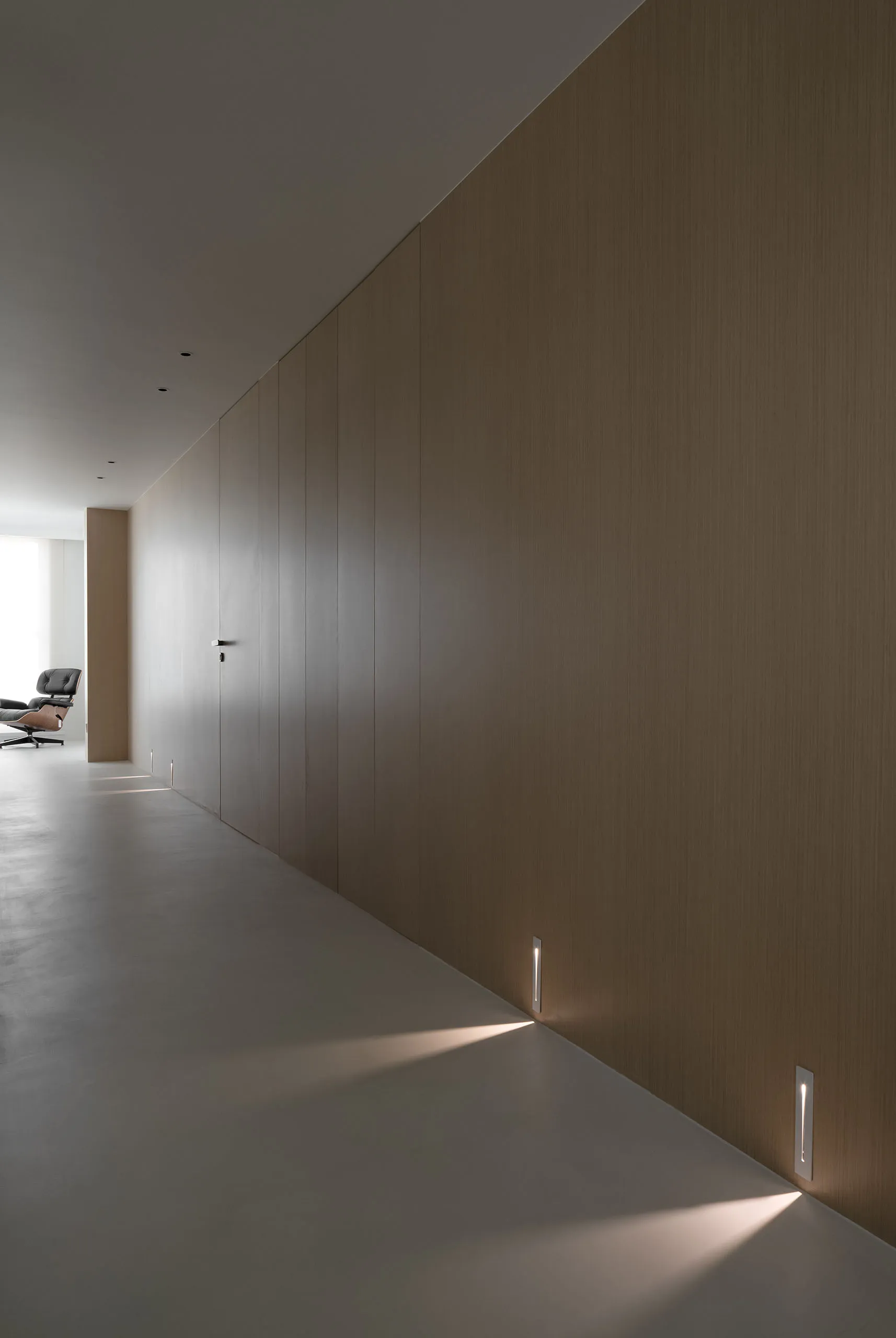 Modern minimalist corridor featuring wood-paneled walls, minimal lighting, and a quiet, unobtrusive atmosphere.